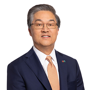 Bobby Kwon wearing a blue suit and a coral tie with glasses