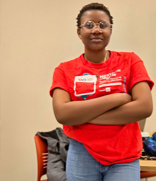 woman in red shirt standing in front of a table and chair