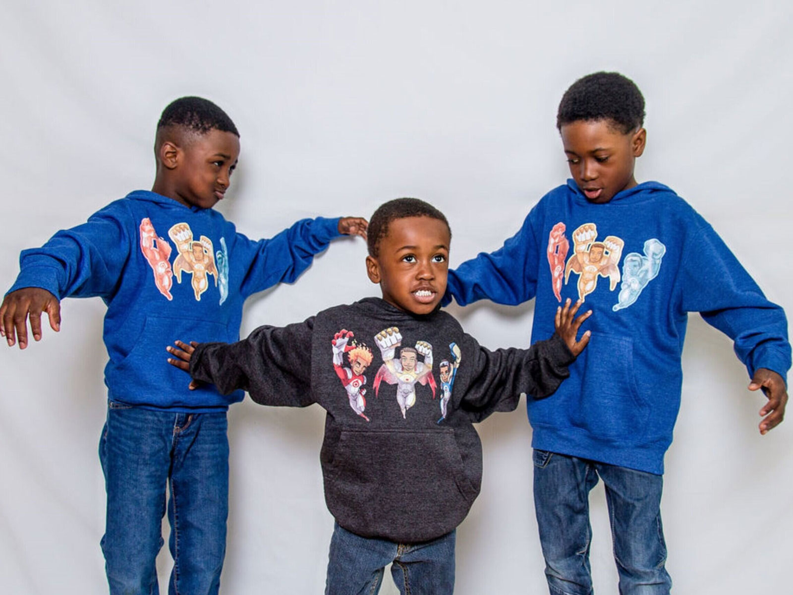 Hezekiah, Joiakim and Micah Felix pose in shirts that display the superhero characters in the book The Battle of Ottogatz.