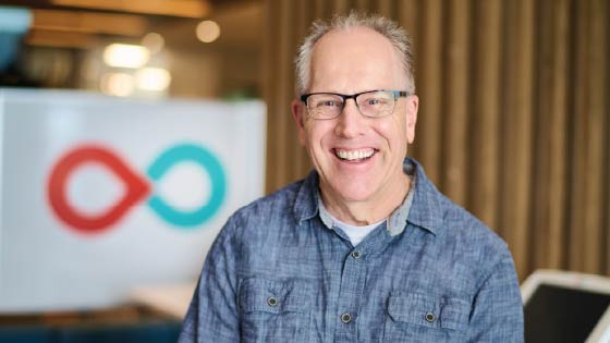 Man in blue shirt smiling with glasses sitting in a donor centre
