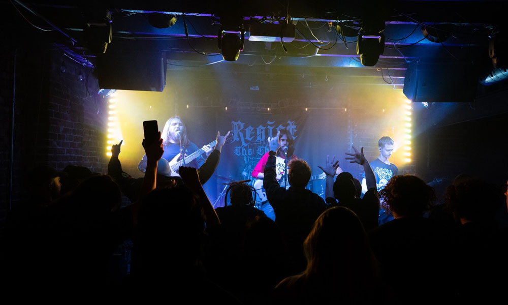 three men on stage playing electric guitars