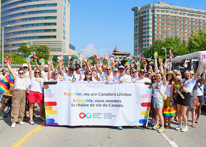 Canadian Blood Services employees holding a large banner for Capital Pride Parade 2024