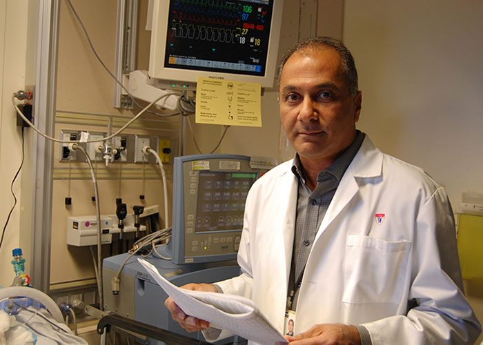 Dr. Shemie holds papers and looks at the camera in a hospital room.