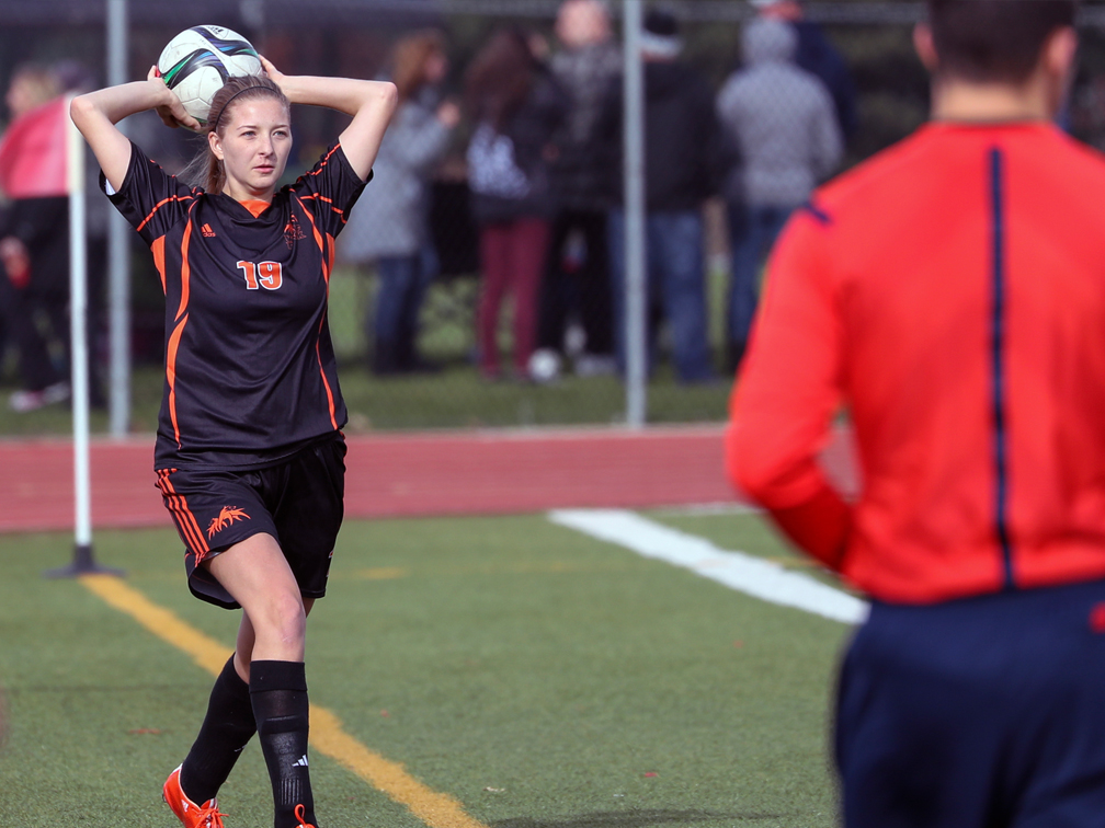 Kelsey Thorkelsson throws a soccer ball in play from the sideline.