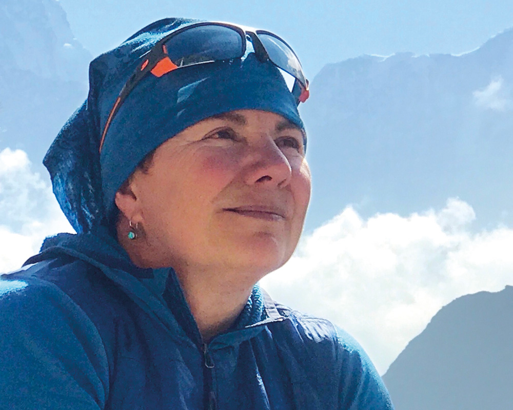 Lucie Dumont sits smiling on a mountain in Nepal