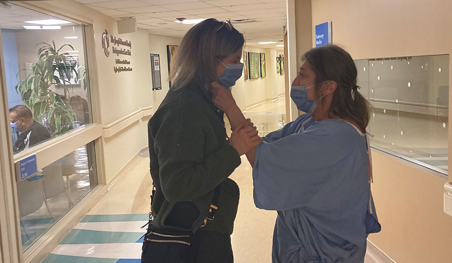 Lucy Latino wearing a hospital gown talking to Claire Yuricek