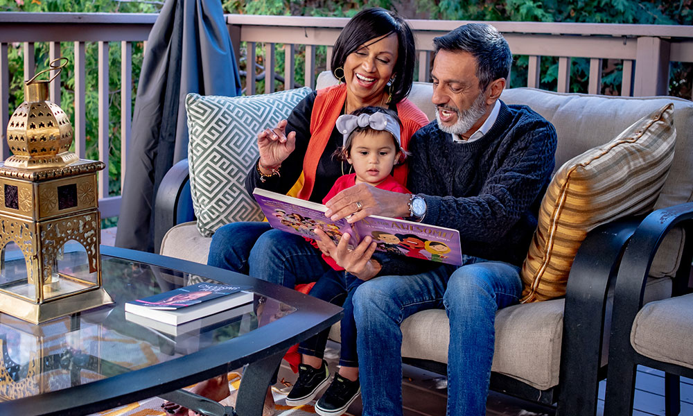 Blood recipient and husband reading to granddaughter on outdoor patio