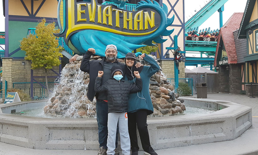Un homme et deux enfants devant une fontaine dans un parc d’attractions