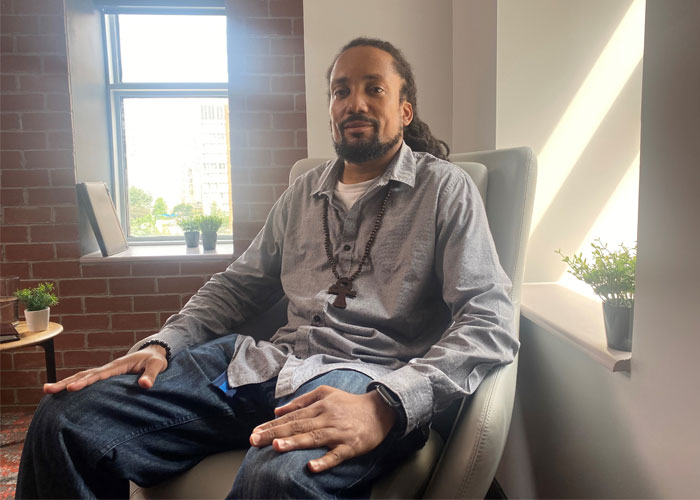 Ulysse Guerrier sits in a chair in his apartment.