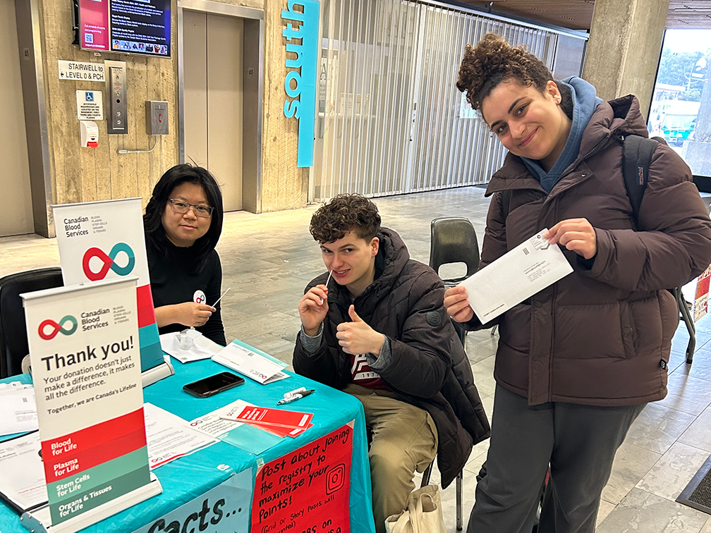 Three students at a registration table.