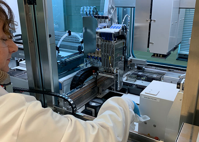 Valerie Conrod in white lab coat opening the machine