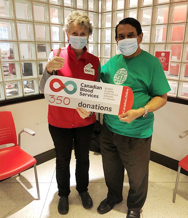 A blood donor with donation sign, and a volunteer