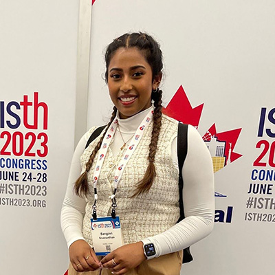 Sangavi standing in front of a signage