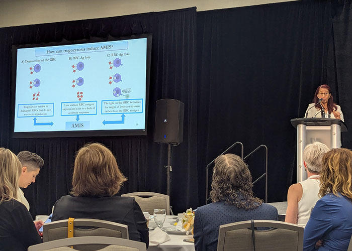 Woman at a podium with a giant screen of the presentation