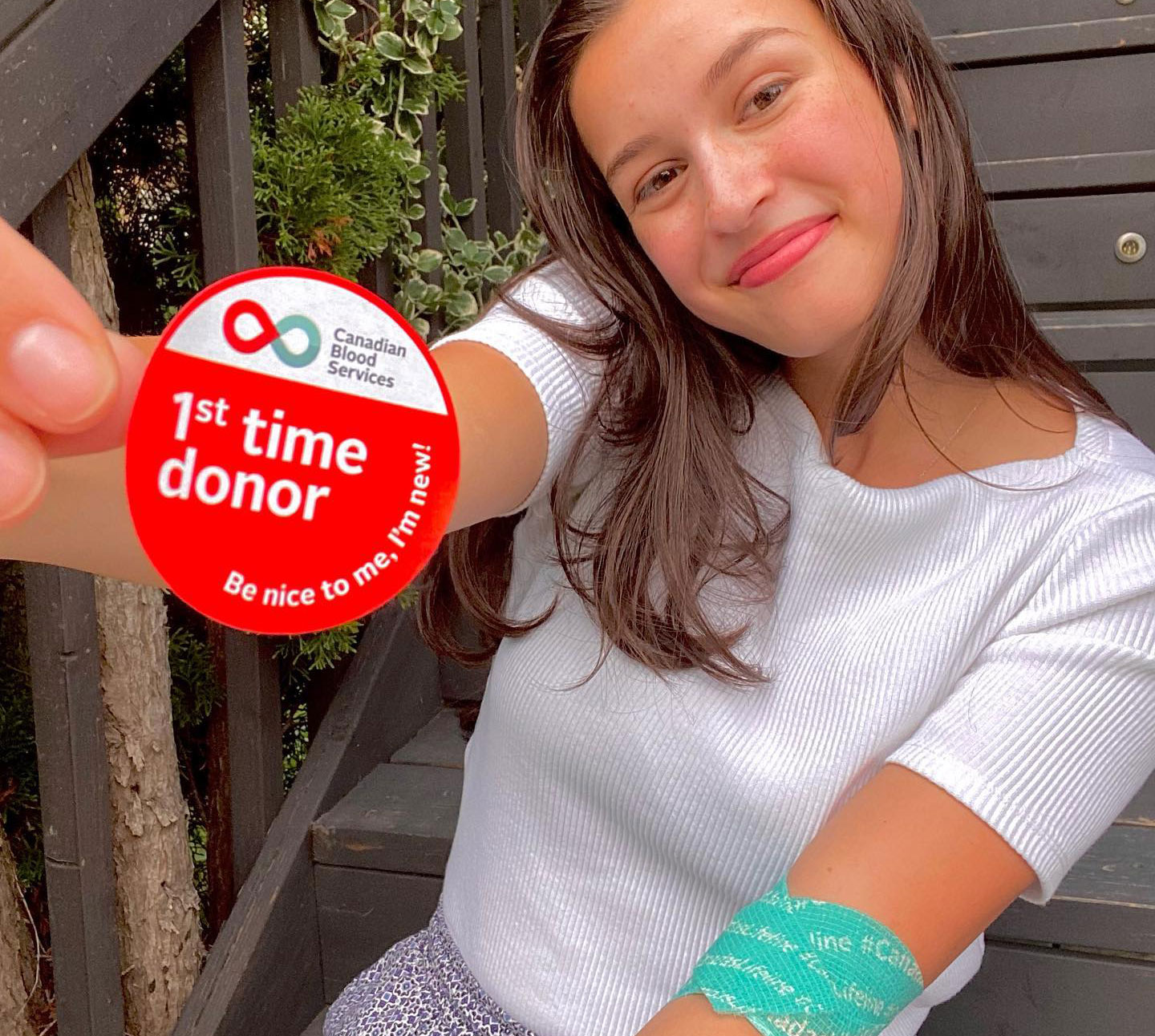 Young woman holding a 1st time donor sticker