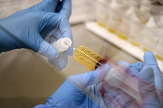 Gloved hands portion plasma into a sterile ophthalmic vial