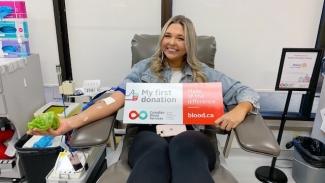 A blood donor in donation chair with a sign that says “first time donation.”