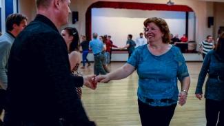 Image of Linda Paul holding her partners hand while swing dancing on the hardwood floor