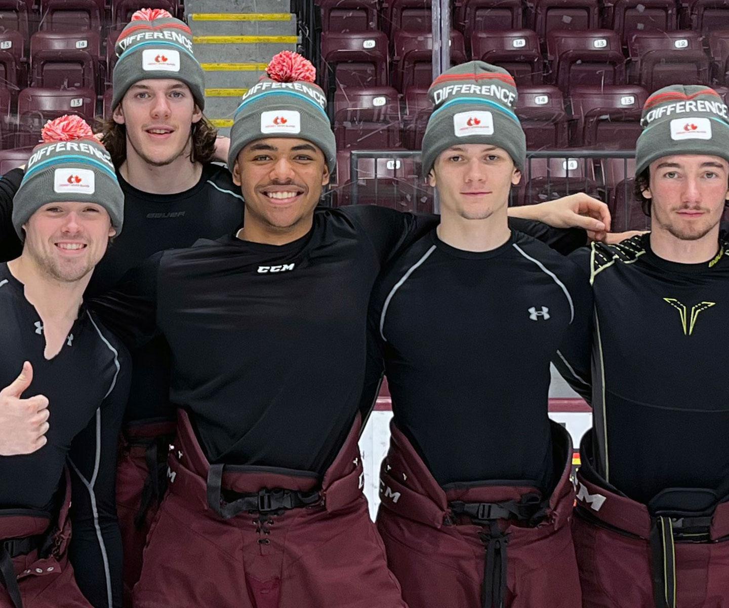 Hockey players on ice with Hockey Gives Blood tuques