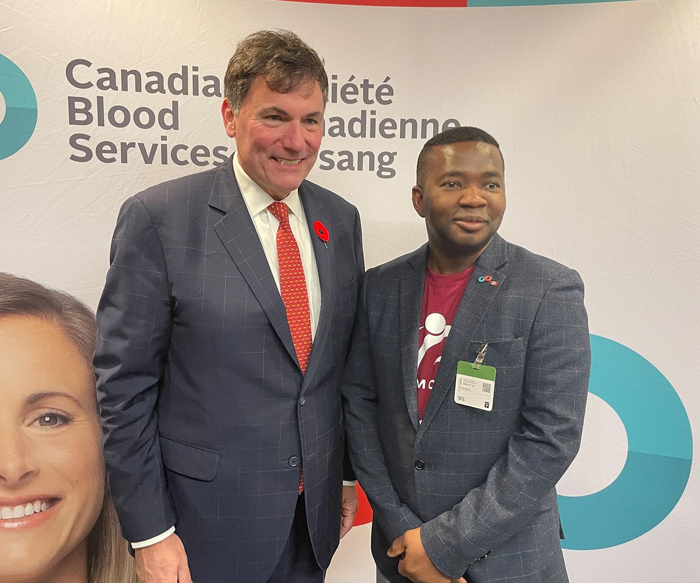 Minister Dominic LeBlanc and Jacob Marfo pose in front of a Canadian Blood Services backdrop