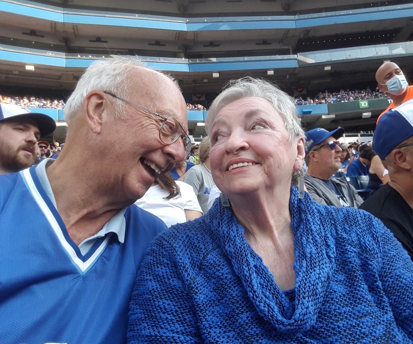 Husband and wife smiling together at baseball game