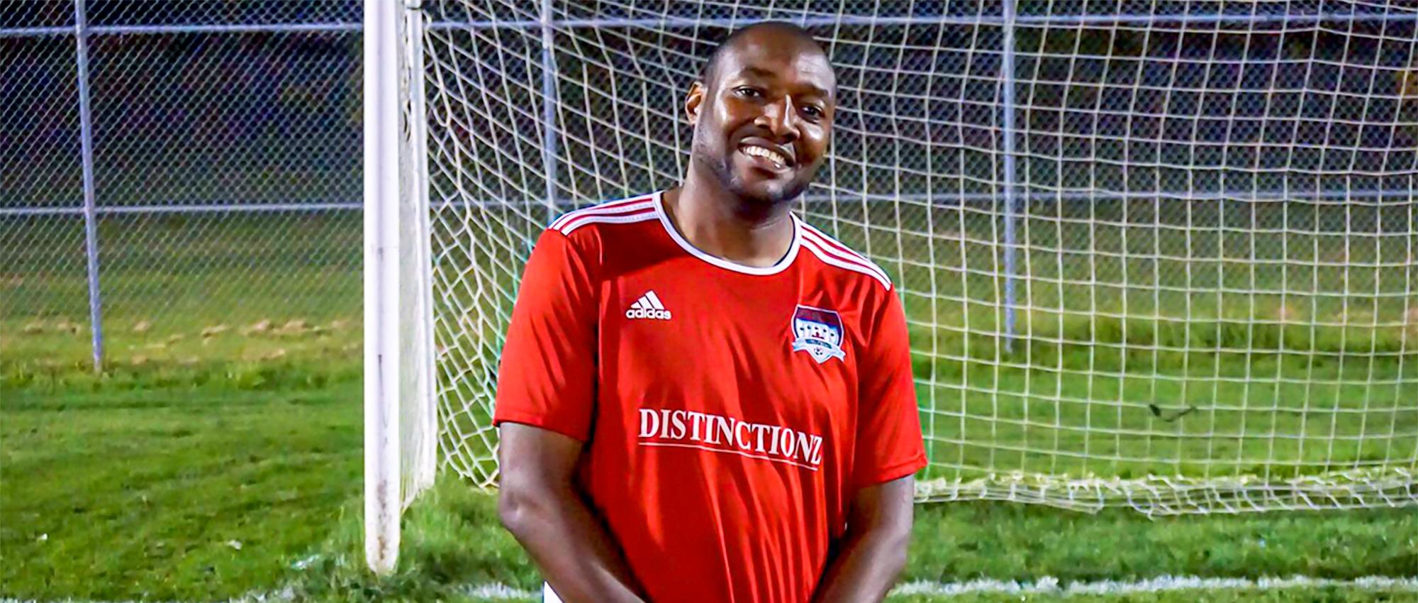 Featured image of Dujon Donaldson wearing a red soccer uniform in front of a soccer goal post