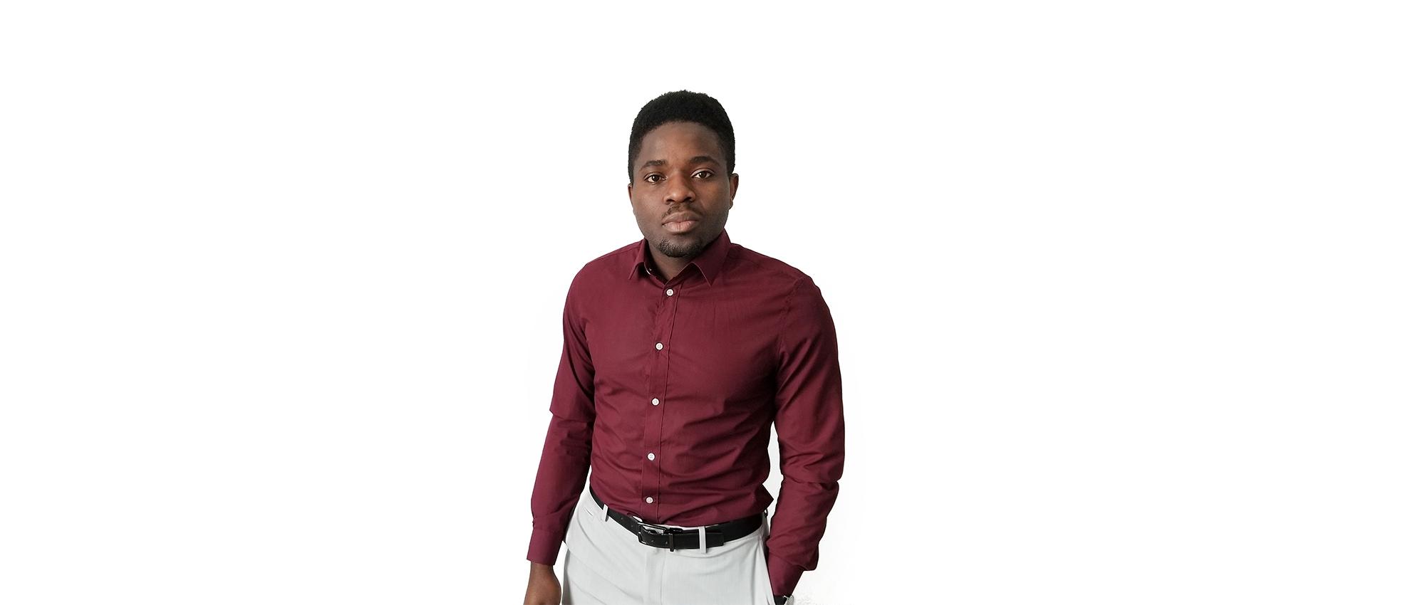 A Black man wearing a red button up shirt in front of a white background.