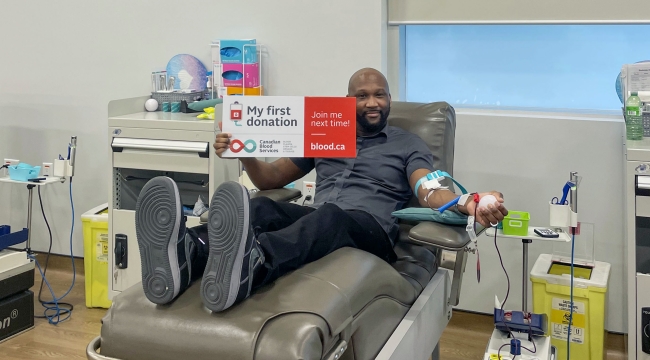 Blood donor in donation chair with sign that says My first donation