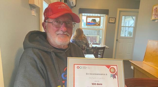 Blood donor holding certificate for 100 donations