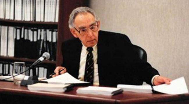 Justice Krever sitting at a desk holding a piece of paper