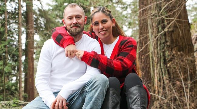 Cord blood donor Lena Mallary and her partner Cory Greenhalgh sit on a fallen tree in a tree park.