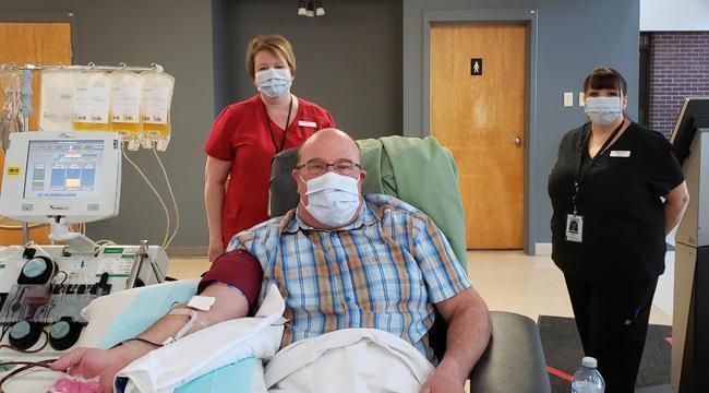 Person in the donor bed with a mask and donating blood with two staff
